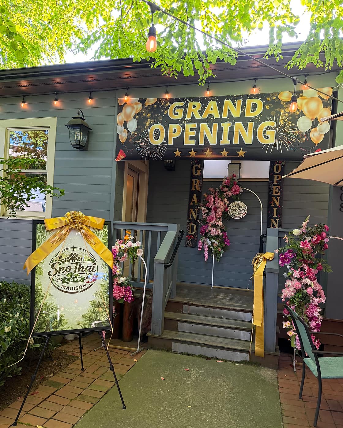 Front porch of Sno Thai Cafe Madison on E Madison Street, Seattle, with grand-opening banner and string lights