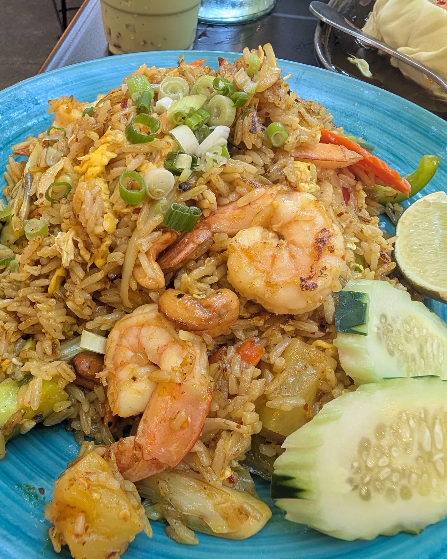 Shrimp fried rice with cashews, pineapple and cucumber on a turquoise plate at Sno Thai Cafe Madison, Seattle